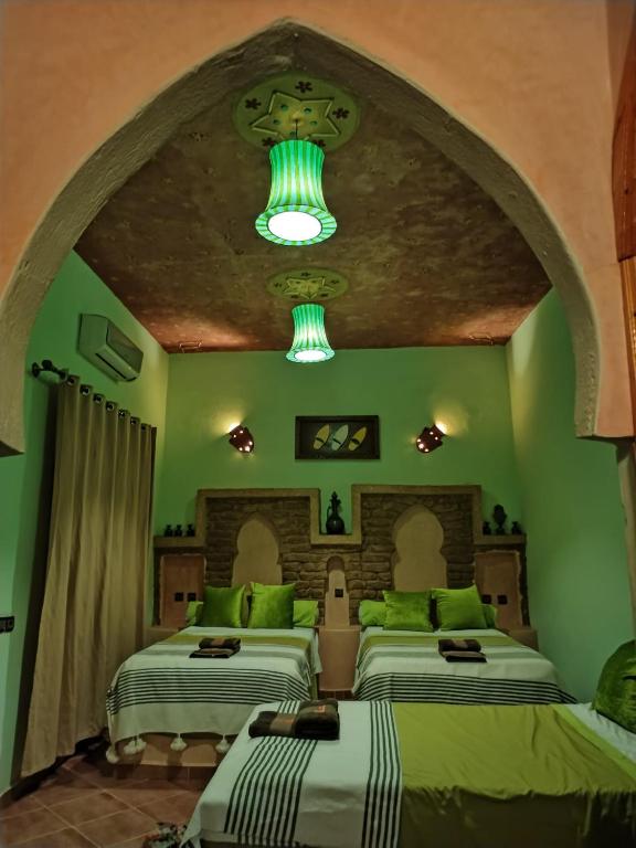 deux lits dans une chambre aux murs verts dans l'établissement Riad Moha, à Merzouga