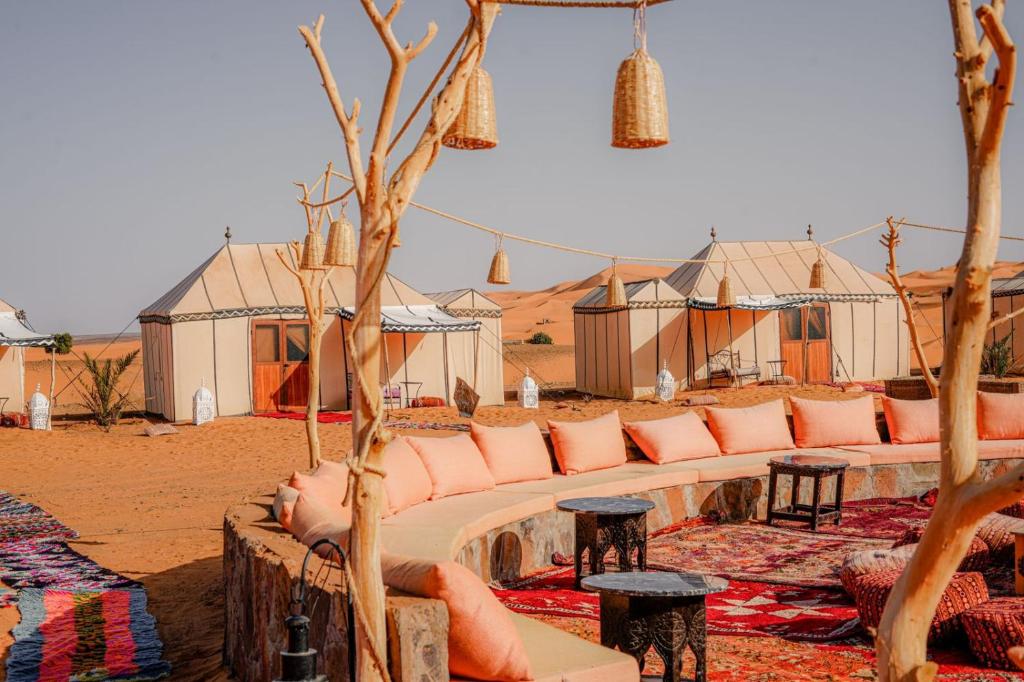 un campement dans le désert avec un canapé, des tables et des tentes dans l'établissement Riad Moha, à Merzouga