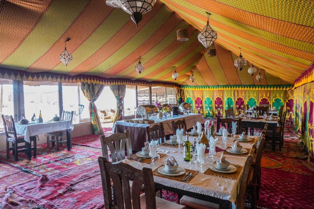 une salle à manger avec des tables et des chaises dans une tente dans l'établissement Riad Moha, à Merzouga
