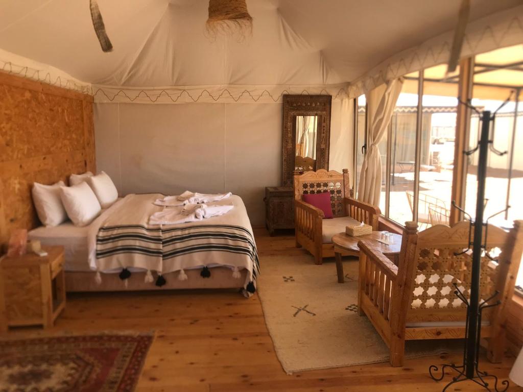 une chambre avec un lit et une chaise dans une pièce dans l'établissement Riad Moha, à Merzouga