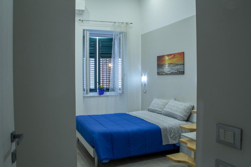 巴勒莫Tourist House Palermo的卧室里有一张铺着蓝色床单的床和一扇窗户