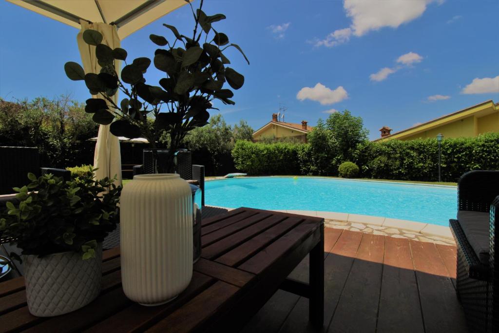 un vase sur une table en bois à côté d'une piscine dans l'établissement Villa di Lago Albano - Castel Gandolfo, à Albano Laziale