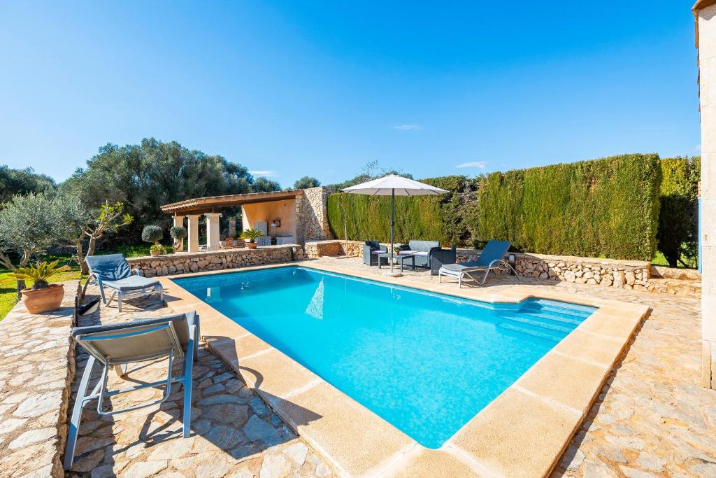 einen Pool mit Stühlen und eine Villa in der Unterkunft Can Pascual in Manacor
