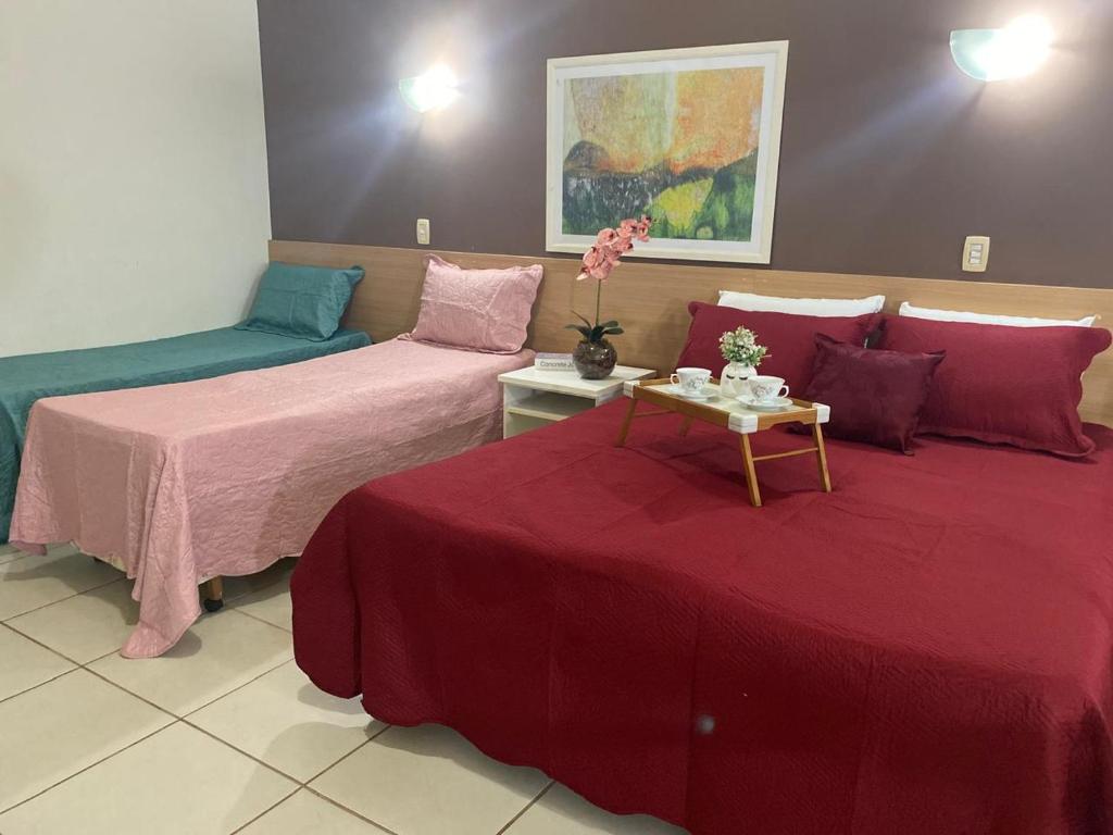 a room with two beds and a table with flowers on it at Aldeia das Águas Village Park Flat A110 térreo in Barra do Piraí