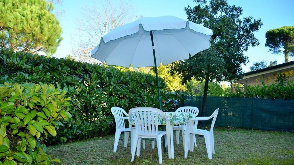 a table and two chairs under an umbrella at Homely flat for 5 in a green area in Bibione in Bibione
