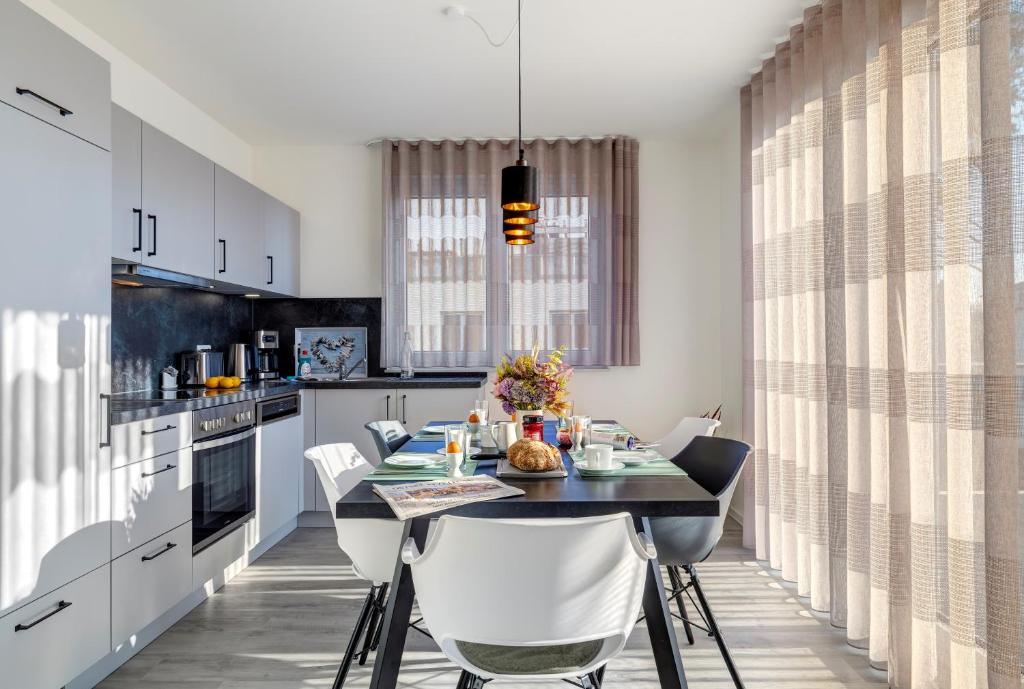 a kitchen with a dining table and white chairs at Apartment B 5 "Pine Hill Resort" in Zirchow
