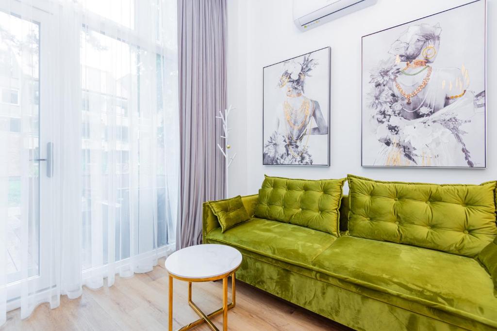 un salon avec un canapé vert et une table dans l'établissement Palanga Beach Apartments Daukanto, à Palanga