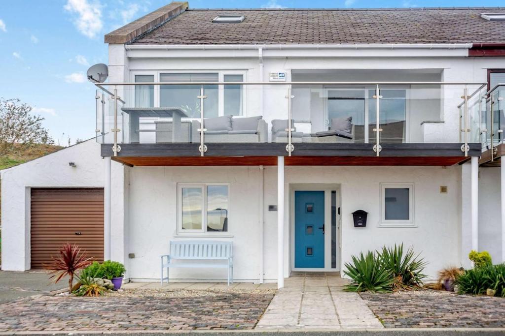 Casa blanca con balcón con puerta azul en Annedd Lon, en Abersoch