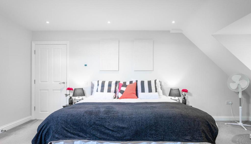 - une chambre blanche avec un grand lit et des oreillers rouges dans l'établissement Garland Penthouse - Large 2 bed 2 bath self contained flat, à Redhill