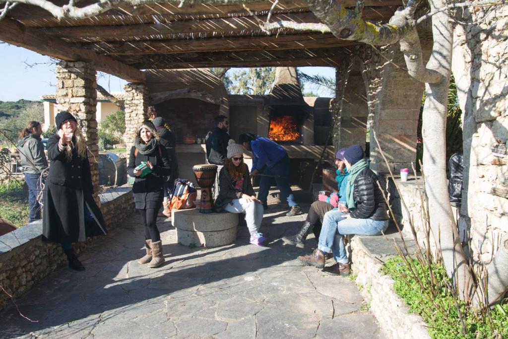 a group of people sitting under a wooden structure with a fireplace at Abramis Rooms in Mitáta