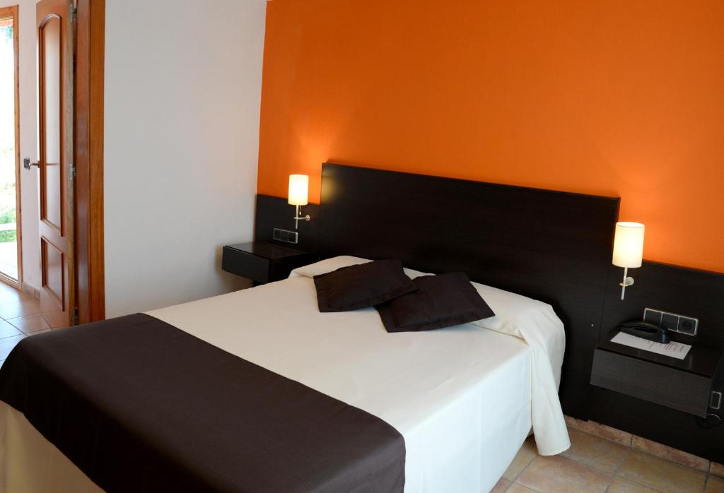 a bedroom with a white bed with an orange wall at Hotel Spa Pinar del Mar in Platja  d'Aro