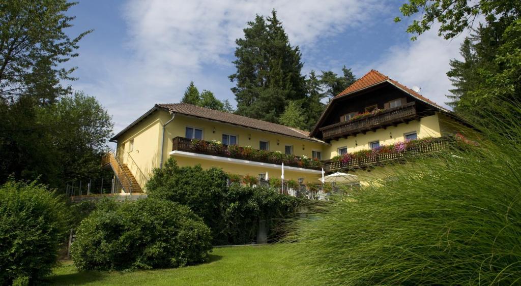 a large yellow house with a balcony in a yard at Pension Appartement Lanzer in Moosburg