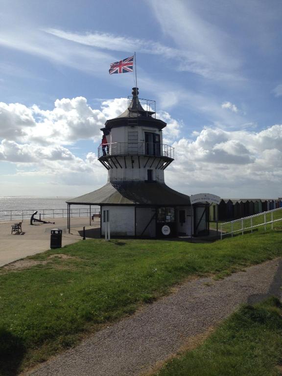 a lighthouse with a flag on top of it on the beach at The Bakehouse in Harwich