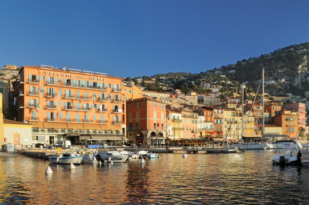 a group of boats docked in a harbor with buildings at Welcome Hotel in Villefranche-sur-Mer