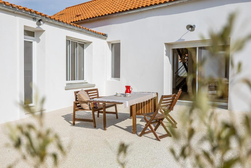 une table et des chaises assises sur une terrasse dans l'établissement Belle villa rénovée aux portes de l'île d'Oléron, à Bourcefranc
