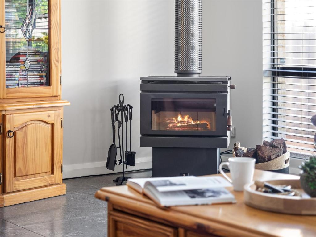 a living room with a fireplace and a table with a book at Busselton Broadwater Holiday Home in Busselton
