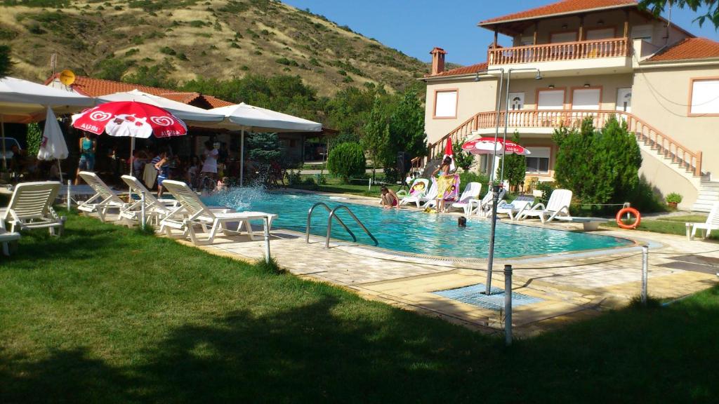 a pool with chairs and umbrellas next to a house at Villa Platythea in Platy