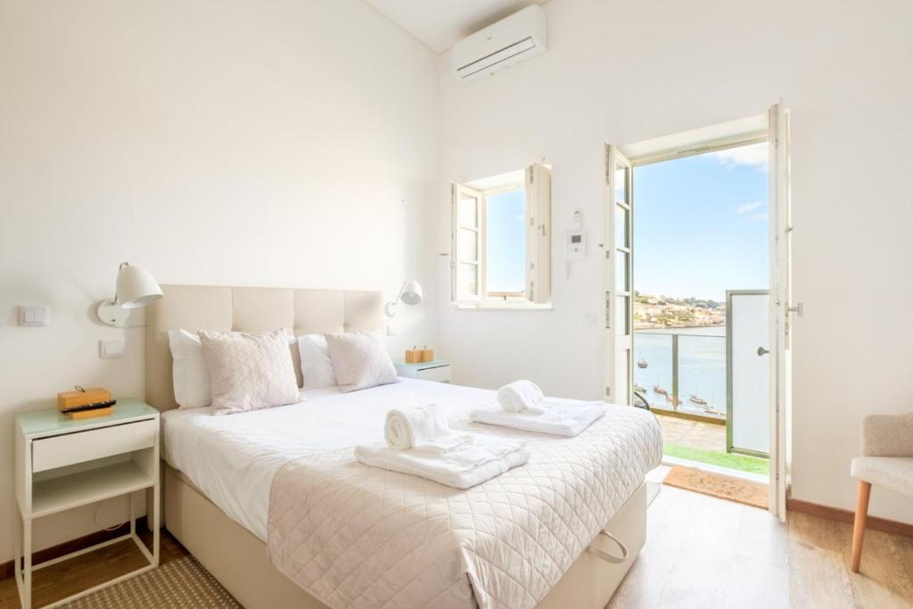 a white bedroom with a bed and a balcony at GuestReady - Port Studio 4 in Bandeira