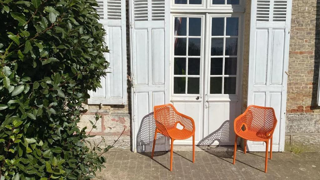 due sedie arancioni sedute davanti a una porta di Appartement charmant à Les Andelys - 36 m² avec jardin a Les Andelys