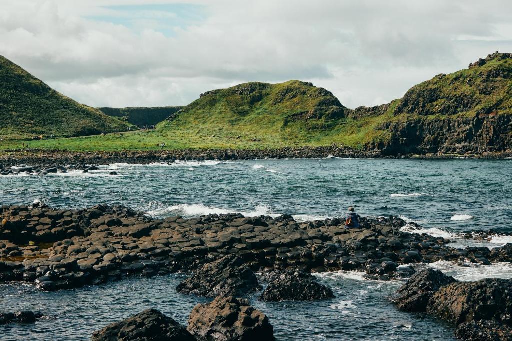 a person sitting on some rocks in the water at Portrush Adelphi in Portrush