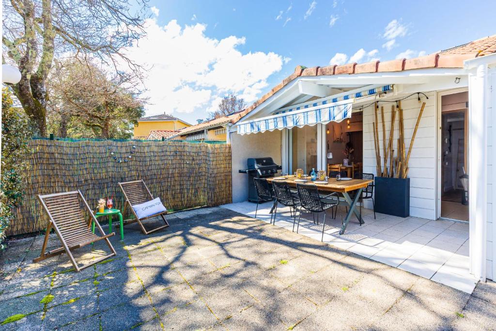 un patio avec une table et des chaises et une clôture dans l'établissement Maison Aturine - Welkeys, à Capbreton