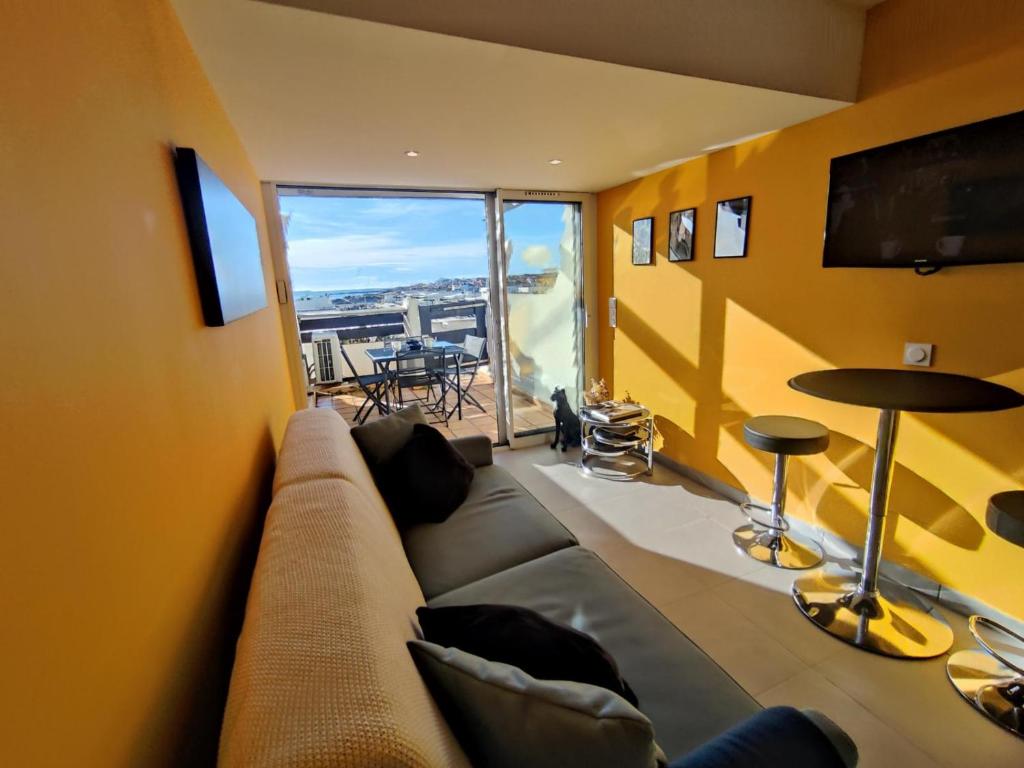 un salon avec un canapé et une grande fenêtre dans l'établissement Appart 76, Port Nature Colline 2 Village Naturiste, au Cap d'Agde