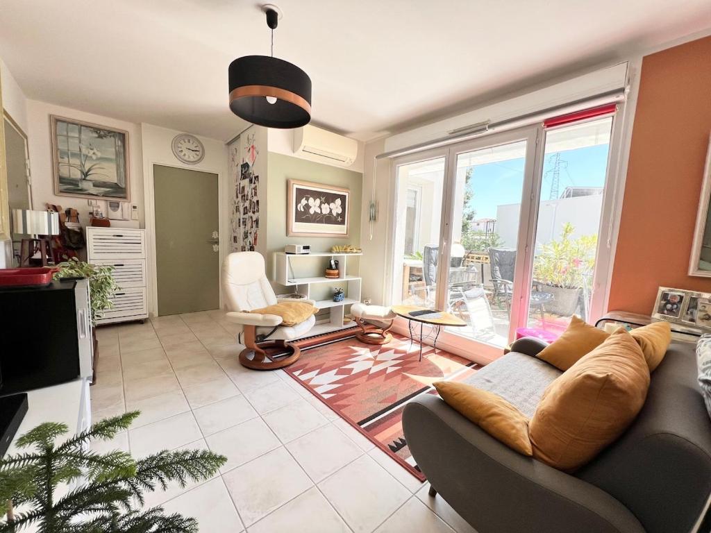 un salon avec un canapé et une télévision dans l'établissement CHEZ MONNA confort , résidence avec piscine, à La Ciotat