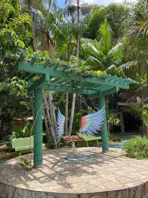 a green pergola with two benches under it at Acomodações Hilton 100 in Ipueiras