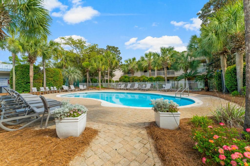 a swimming pool with benches and palm trees at 30A - Cassine Station by Panhandle Getaways in Santa Rosa Beach