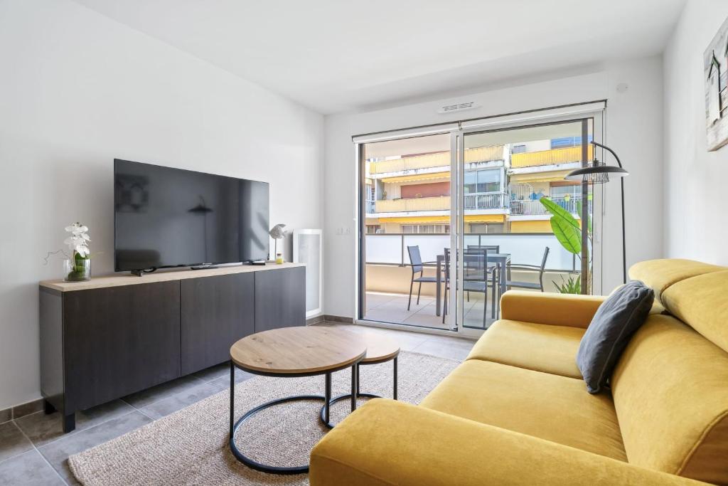 - un salon avec un canapé jaune et une télévision dans l'établissement Appartement Amandiers - Welkeys, à Cagnes-sur-Mer
