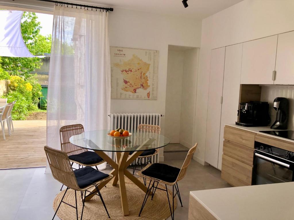une cuisine avec une table en verre et des chaises dans une pièce dans l'établissement Maison familiale équipée, centre-ville, au Mans