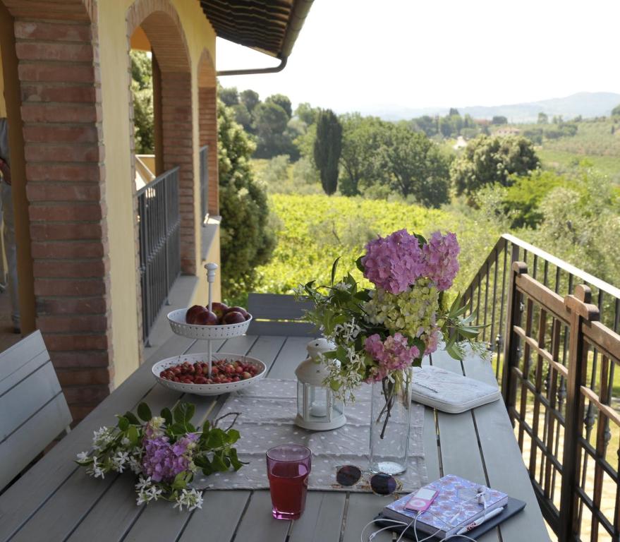 uma mesa com frutas e flores numa varanda em Agriturismo Renai e Monte II em Gambassi Terme