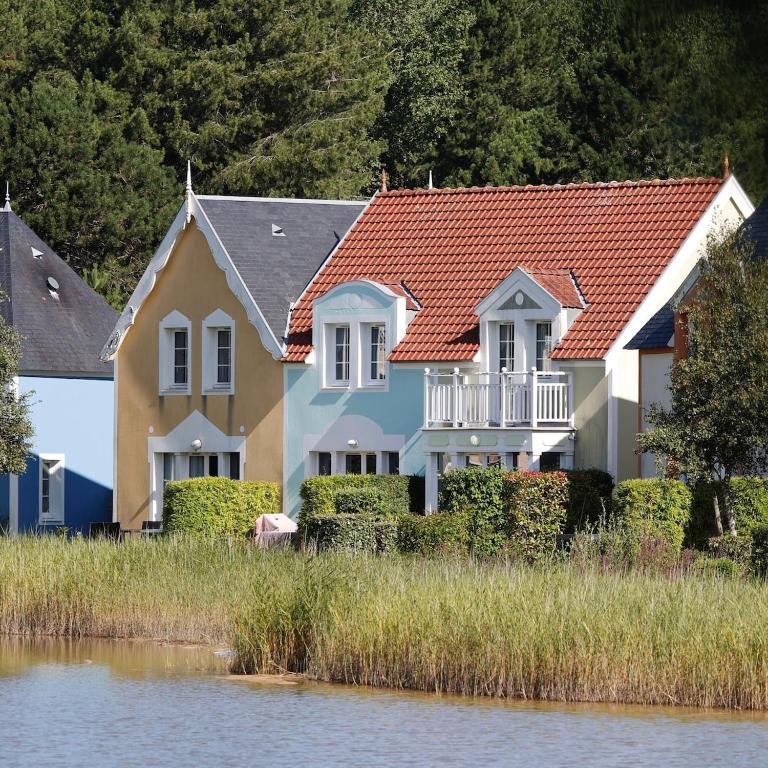 une maison avec un toit rouge à côté d'une masse d'eau dans l'établissement Maison Belle Dune L'Île aux Oiseaux 34, à Quend-Plage