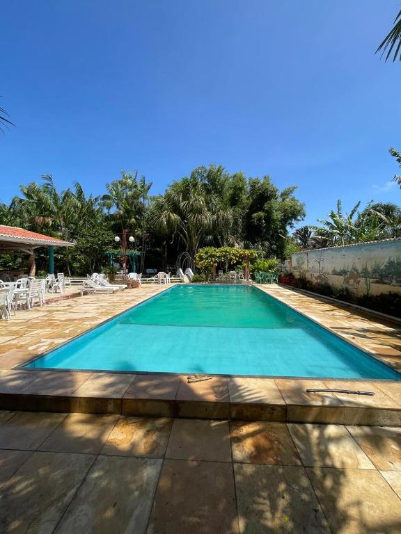 una piscina azul con sillas y árboles en acomodações hilton 100, en Ipueiras