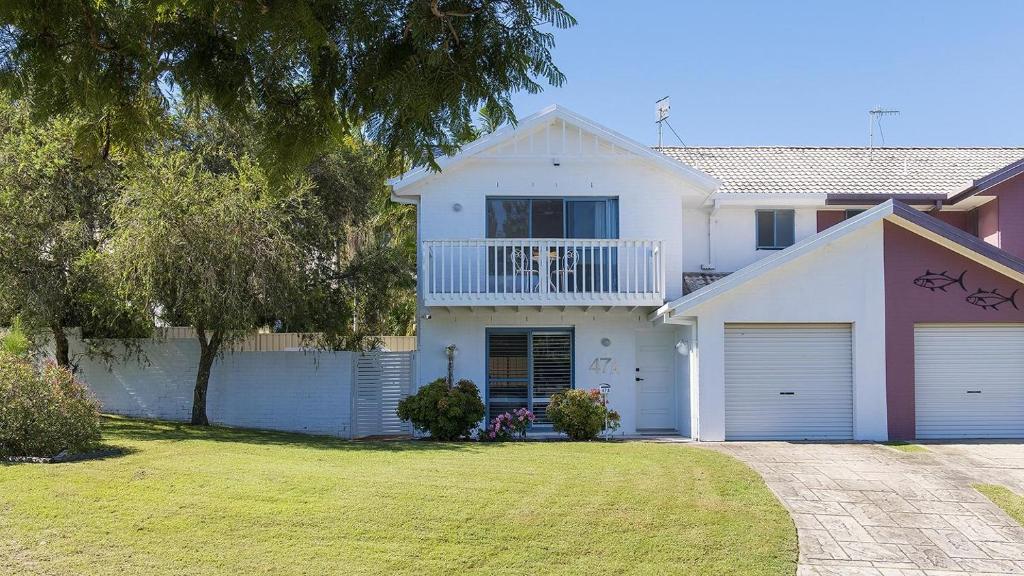 Una casa blanca con un balcón encima. en Coastal Hideaway - Water Views and Walk To The Beach, en Corlette