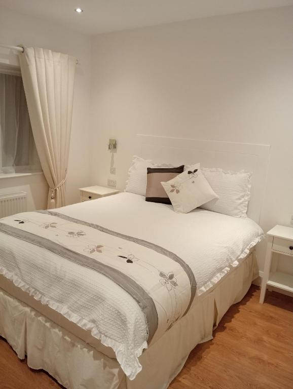um quarto com uma cama branca com lençóis brancos em Hayes House Killarney em Killarney