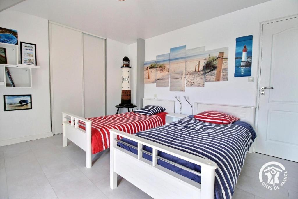 a bedroom with two beds and a lighthouse on the wall at Les saudraies - unite familiale in Rieux