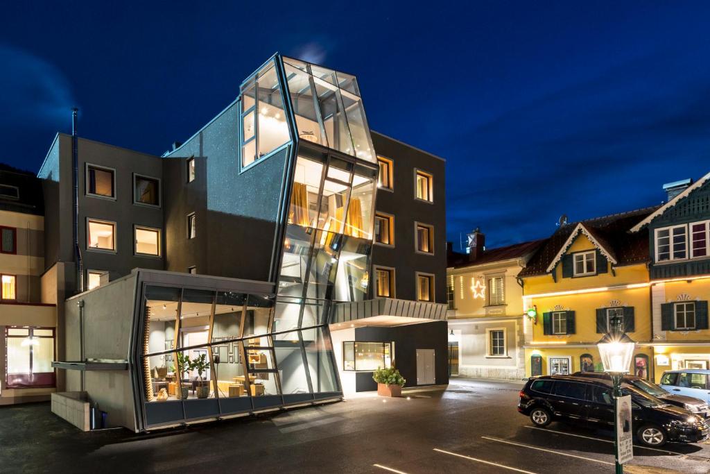 a glass house in a parking lot with buildings at Stadthotel Brunner in Schladming