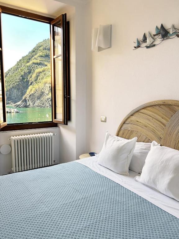 ein Schlafzimmer mit einem großen Bett und einem großen Fenster in der Unterkunft Ca der Duse in Vernazza