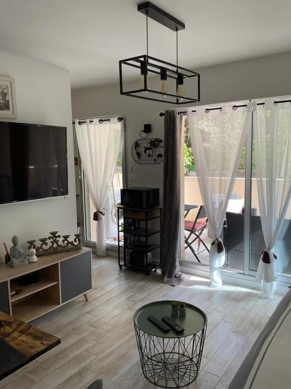 a living room with a table and a large window at Studio coin nuit terrasse parking Clim in Nice