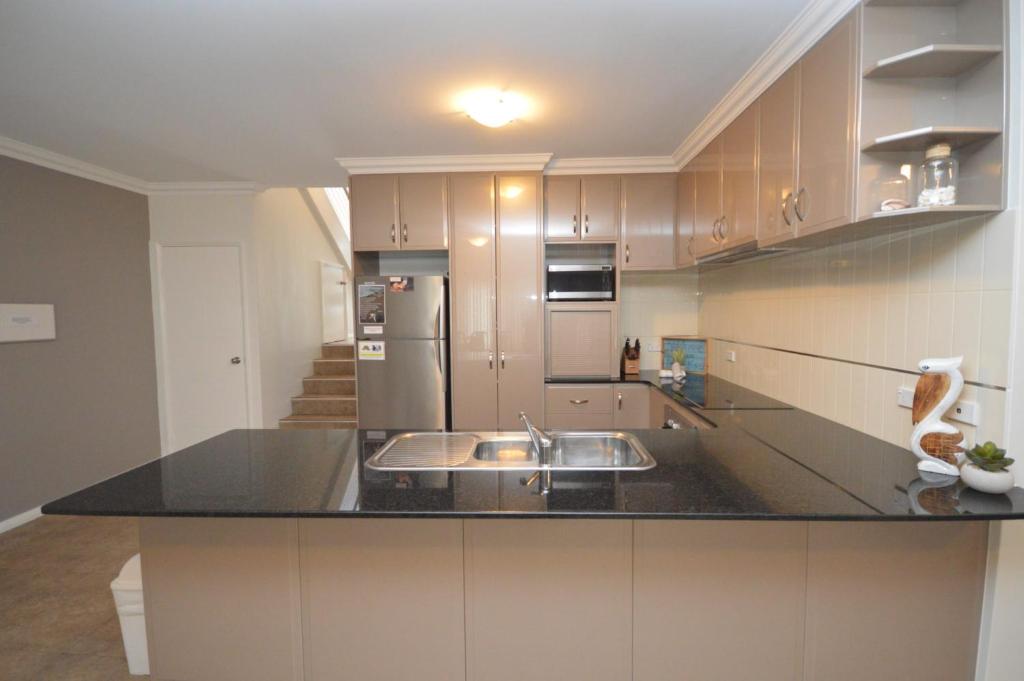 a kitchen with a sink and a refrigerator at Villa Palazzo 3 - Kalbarri, WA in Kalbarri