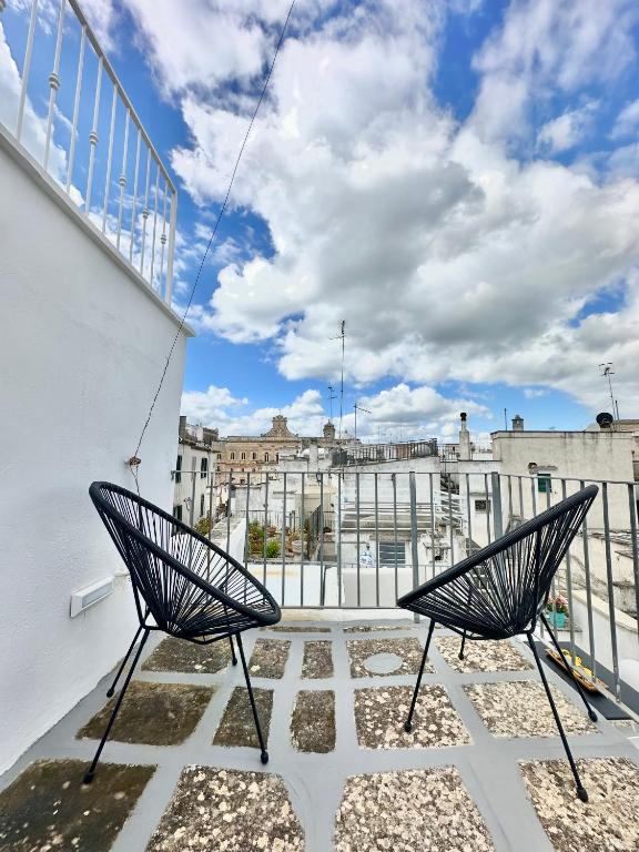 a balcony with two chairs and a view of a city at CASSIODORO - Home & Terrace in Ostuni