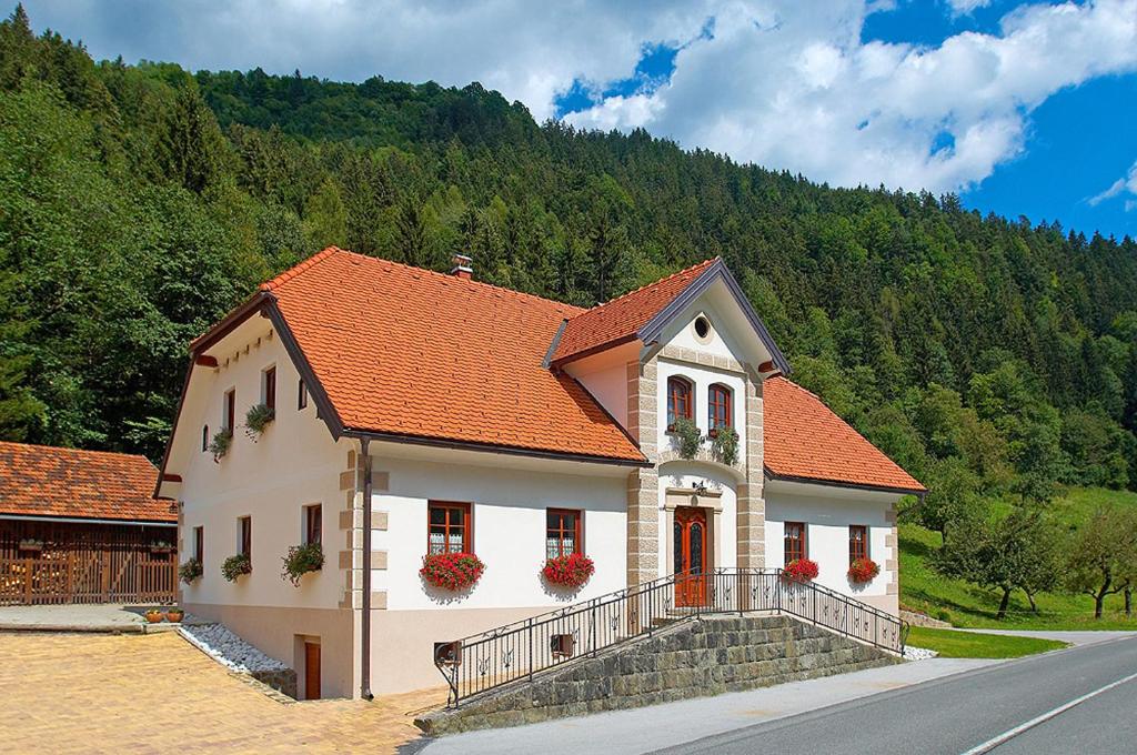 a white house with an orange roof with flowers on it at Farm stay Bukovje in Ljubno