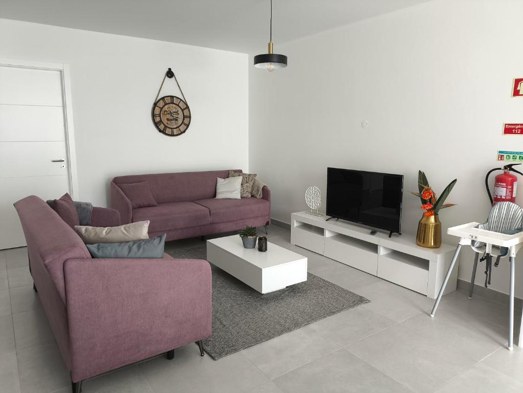 a living room with a purple couch and a tv at Waves and Trails in Porto Covo
