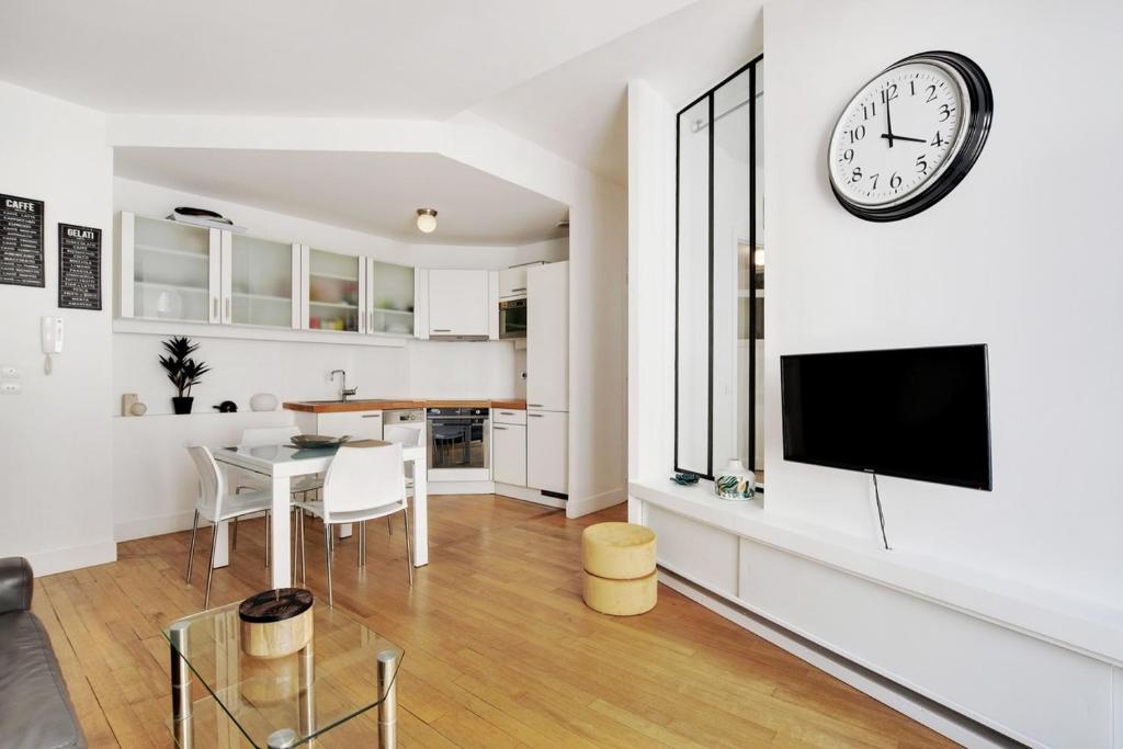 un salon avec une table et une horloge murale dans l'établissement Moderne 3 pièces au coeur des Champs-Elysées, à Paris