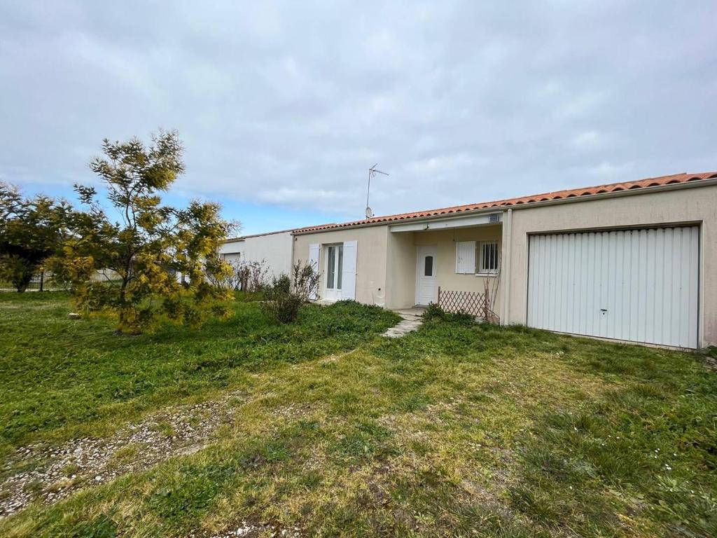 une maison avec un garage et une pelouse dans l'établissement Ile d'Oléron - Saint Georges d'Oléron- Maison 5 couchages SGO000-128, à Saint-Georges-dʼOléron