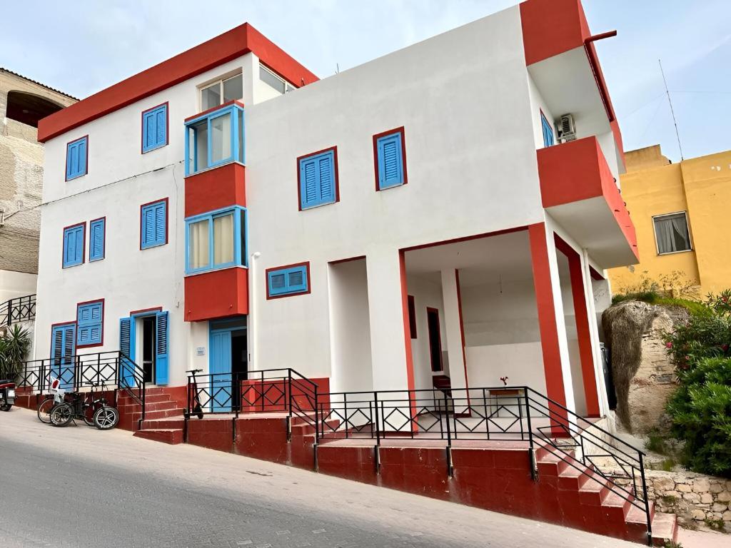 Un edificio blanco y rojo con ventanas azules. en Casa Lipadusa, en Lampedusa