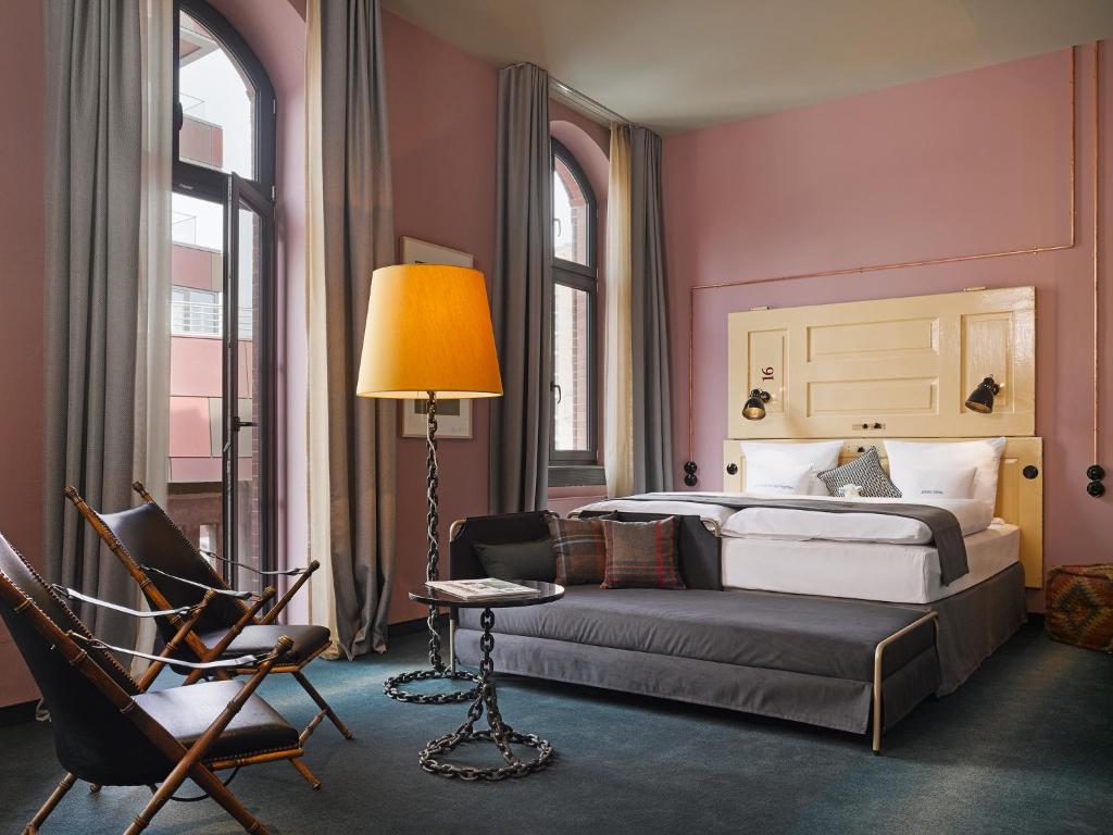 a bedroom with a bed and a chair and a lamp at 25hours Hotel Altes Hafenamt in Hamburg