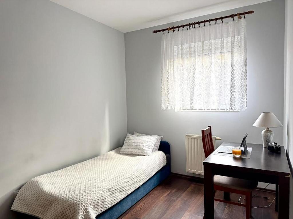 a bedroom with a bed and a desk and a window at Taras Słoneczny in Kielce