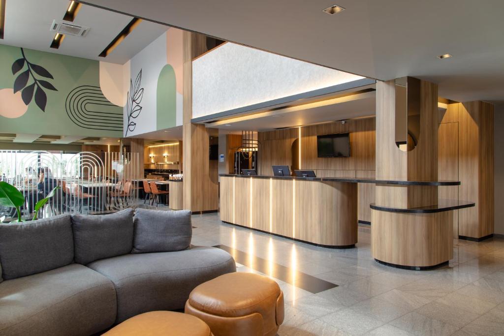 a lobby with a couch and a bar at Slim Curitiba Alto da XV in Curitiba